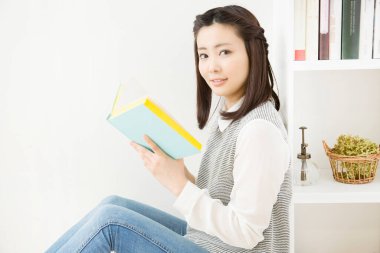 Evde kitap okuyan genç bir kadın. 