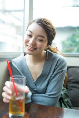 Güzel Asyalı kadın kafede soğuk içecek içiyor.