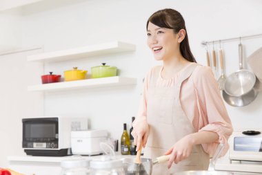 Asyalı genç bir kadın mutfakta yemek pişiriyor.