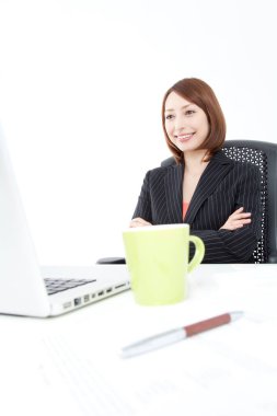 Genç Asyalı iş kadını ofiste dizüstü bilgisayarla çalışıyor.