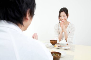 Asyalı kadın ve erkek birlikte yemek yiyorlar.