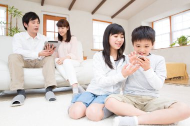 Oturma odasında alet kullanan dört kişilik genç bir aile. 