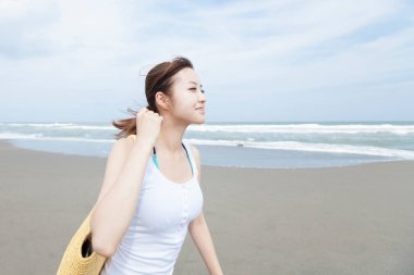 Kumsalda çanta taşıyan genç Asyalı kadın.