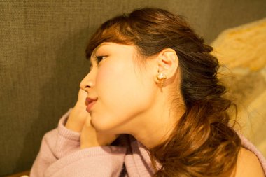 Genç kadın evde otururken üzgün.