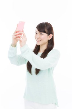 Beyaz arka planda selfie çeken genç bir kadın. 