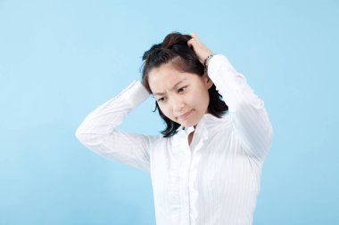 Genç Asyalı kadın hasta ve baş ağrısı var üzerinde mavi arka plan