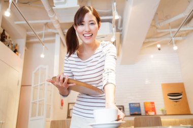 Ahşap tepside kahve servisi yapan genç Japon garson.