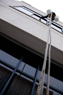 Dışarıdaki uzun ip merdiveni kullanarak pencereden kaçan biri.