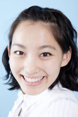 Mavi arka planda gülümseyen güzel bir genç kadının portresi. 