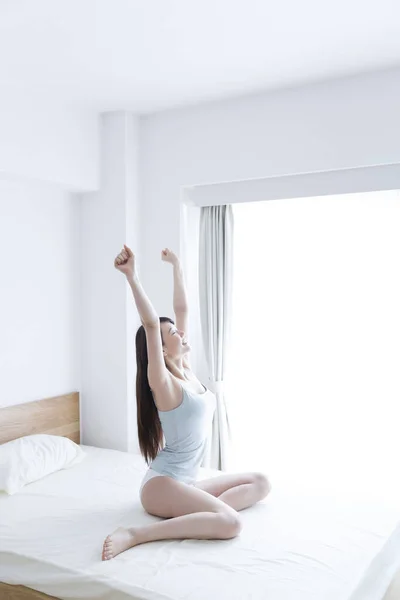 young girl stretching her arms in her bed at home, stretching up