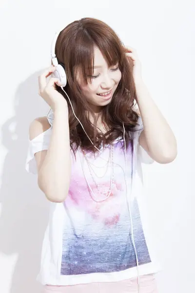 ヘッドフォンで音楽を聴くアジアの女性は — ストック写真