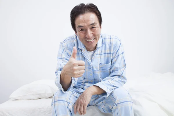 asian man in pajamas showing thumb up