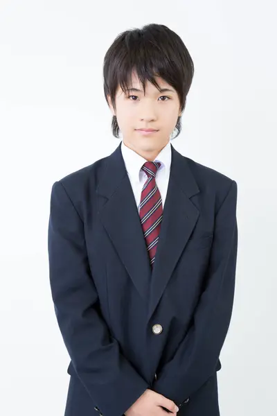 stock image Portrait of Japanese teenager in uniform standing on white studio background 