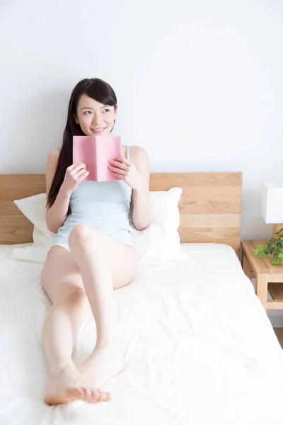 young asian woman read book on bed at bedroom
