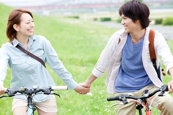 年轻夫妇在夏季公园骑自行车 健康生活方式概念 — 图库照片