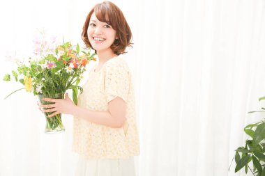 Bir buket taze çiçekle gülümseyen genç Japon kadın.