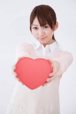 Genç Asyalı kadın elinde kırmızı kalp kutusu tutuyor.