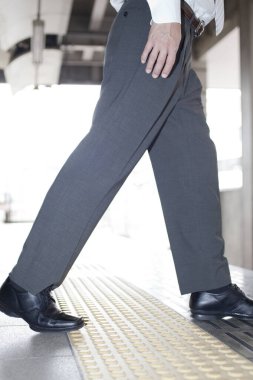 İş adamı tren peronunda duruyor. 