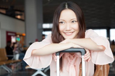 Havaalanı terminalinde bavullu güzel bir Japon kadın. seyahat ve tatil kavramı
