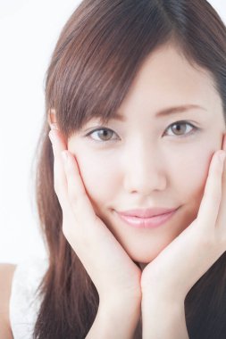 Genç, güzel Asyalı bir kadın. Yüzü asık, soyutlanmış arka planda poz veriyor.  