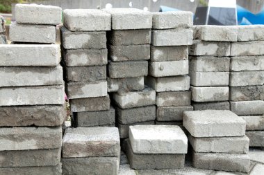 Dışarıdaki inşaat sahasına beton kaldırım taşları yığılmış.