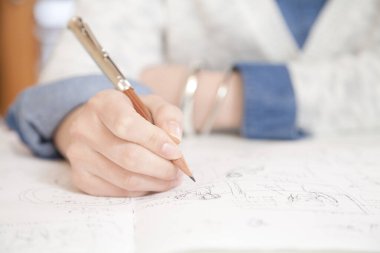 kadın mimar plan üzerinde çizim yapıyor