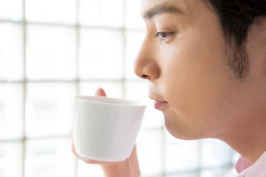 Genç adam fincanda çay içiyor..