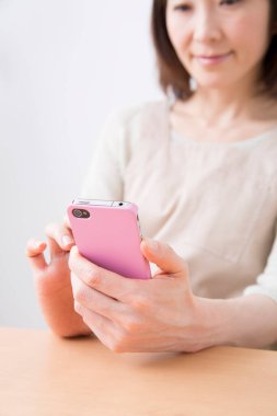 Mutlu genç Asyalı kadın cep telefonu kullanıyor.