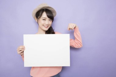 Boş beyaz pankartıyla gülümseyen Asyalı genç kadın.