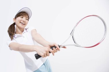 Beyaz stüdyo arka planında tenis oynayan Asyalı kadın