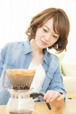 Gülümseyen Japon kadın kahve yapıyor.