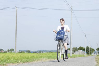 Kırsalda bisiklet süren gülümseyen Asyalı kız.