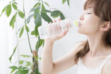 Kadın evde maden suyu içiyor. 