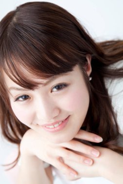 Beyaz gömlekli genç bir kadın beyaz arka planda poz veriyor.