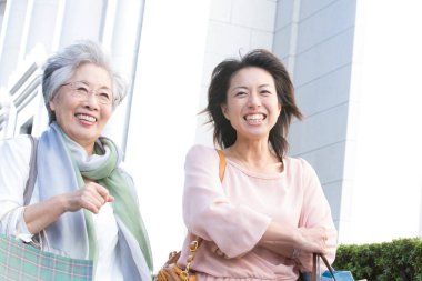 İki kadın alışveriş torbalarıyla kaldırımda yürüyorlar.