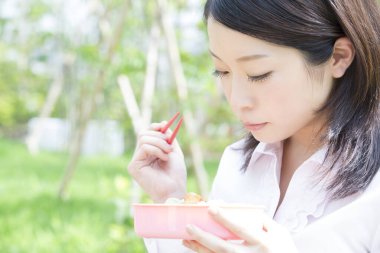 Parkta Japon yemeği yiyen bir kadın. 