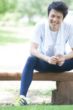 Parkta koştuktan sonra suyla gelen genç adam. 