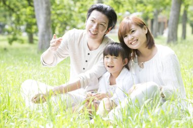 Mutlu Japon ailesinin portresi yaz parkında dinleniyor.