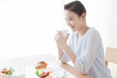 Güzel Asyalı kadın kahvaltısını evde yapıyor.