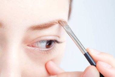 Kadın fırçayla kaş pudrası sürüyor. 