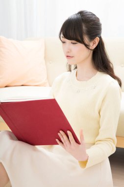 Evde kitap okuyan güzel Asyalı kadın