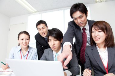 Dizüstü bilgisayarla çalışan bir grup genç Japon iş adamı.