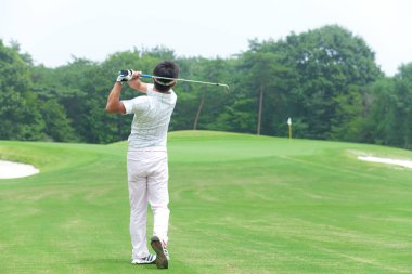 Genç Japon adam gündüz golf oynuyor. 