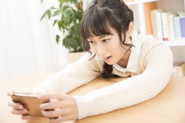 Güzel Asyalı genç kadın akıllı telefon kullanıyor.