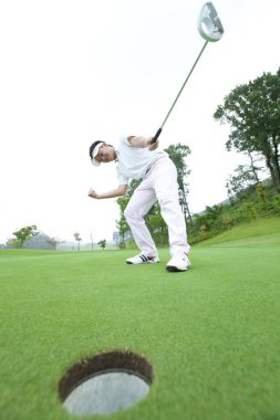 Genç Japon adam gündüz golf oynuyor. 