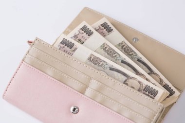 Japon banknotlarıyla dolu pembe kadın cüzdanı. Beyaz arka planda. 