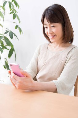 Mutlu genç Asyalı kadın cep telefonu kullanıyor.