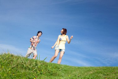 Genç bir çift yaz günü plajda koşuyor.