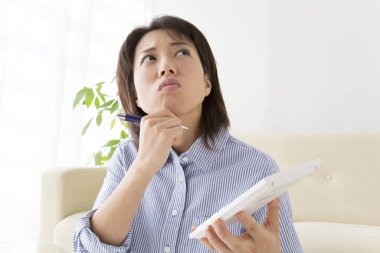 Kanepede oturan bir kadın elinde hesap makinesi tutuyor.