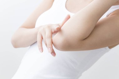 Genç Asyalı kadın dirseğine dokunuyor, stüdyo çekimi. 